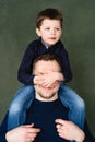 Boy is sitting on his father shoulders, covers dad face with his hands Royalty Free Stock Photo